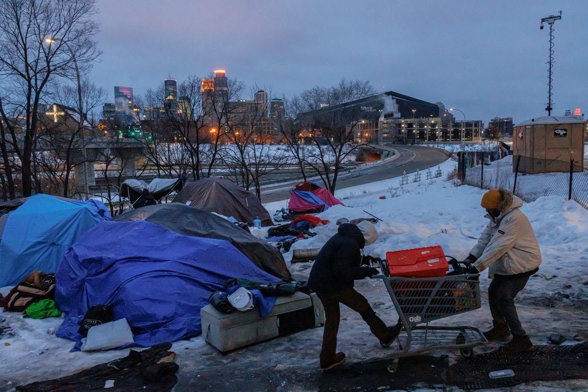 Cedar Riverside encampment residents push to cart near 15th Avenue South and 6th Street South in Minneapolis on Wednesday. The camp will be evicted this morning because it was the scene of a fatal shooting last week.