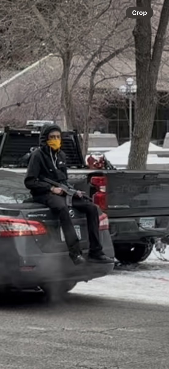 Anti-ICE protester sits on a vehicle holding a gun in Minneapolis